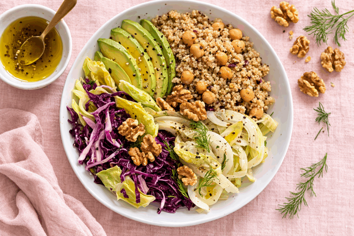 Insalata di quinoa con avocado, finocchi, indivia e noci su tovaglia di lino rosa pallido