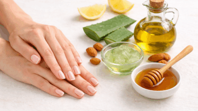 Mani curate con unghie naturali e rinforzate accanto a olio d’oliva, aloe vera e miele