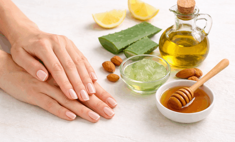 Mani curate con unghie naturali e rinforzate accanto a olio d’oliva, aloe vera e miele