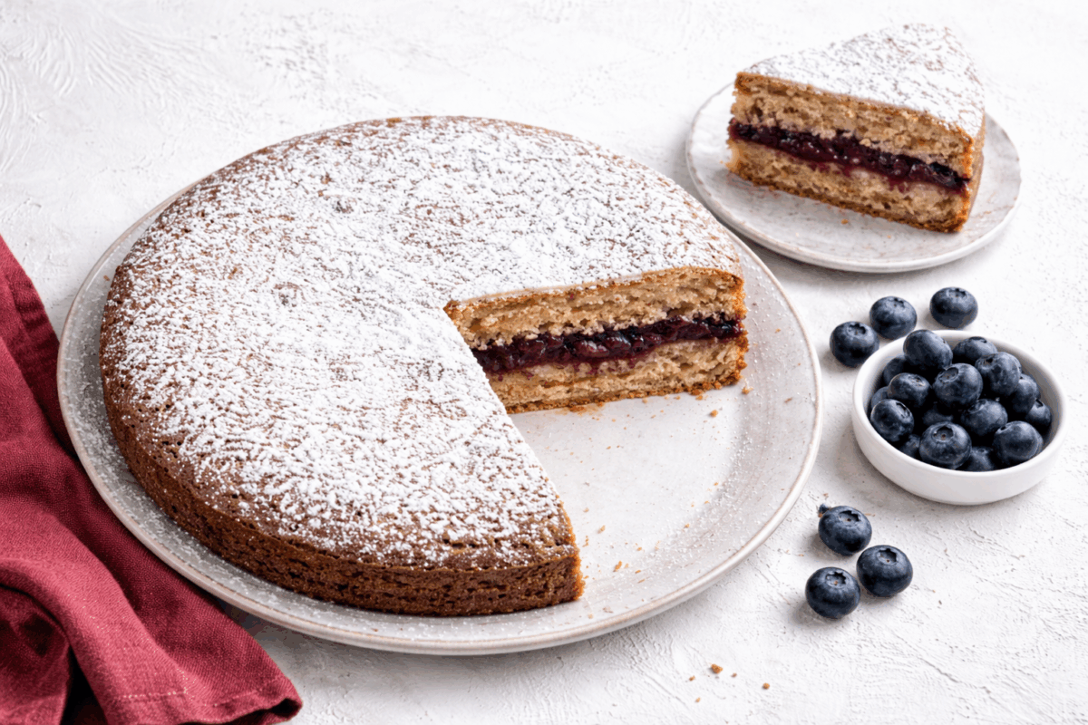 Torta di grano saraceno senza glutine con farcitura di marmellata di mirtilli su piano chiaro con mirtilli freschi