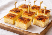 Torta di riso vegana senza uova, latte e burro con crosta caramellata, tagliata a quadratini su tagliere di legno