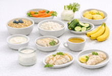 Tavola con i 12 cibi consigliati per il reflusso: avena, riso bianco, patate lesse, banane, zucchine, carote, finocchio, yogurt naturale, carni bianche, pesce magro e camomilla