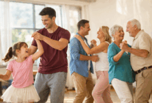 Bambina, giovane adulto e coppia di anziani che ballano insieme in una sala luminosa con luce naturale, esempio dei benefici della danza per corpo e mente a tutte le età