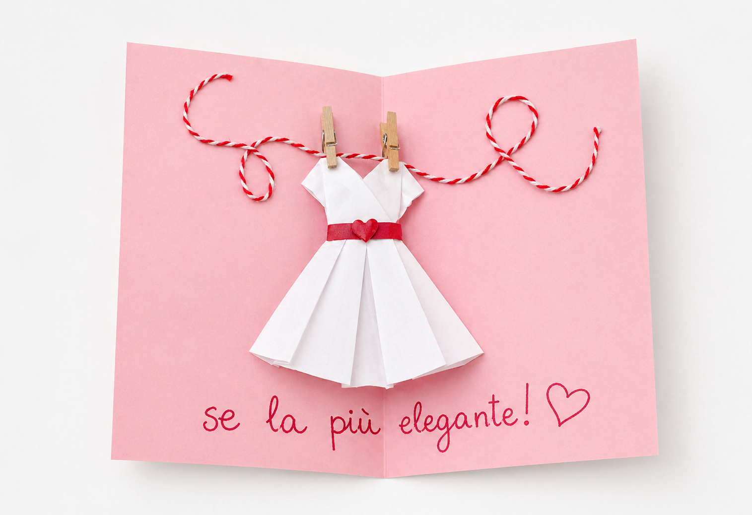 Biglietto fai da te per la Festa della Mamma con vestito di carta bianco, cintura rossa e scritta “Sei la più elegante” su sfondo rosa