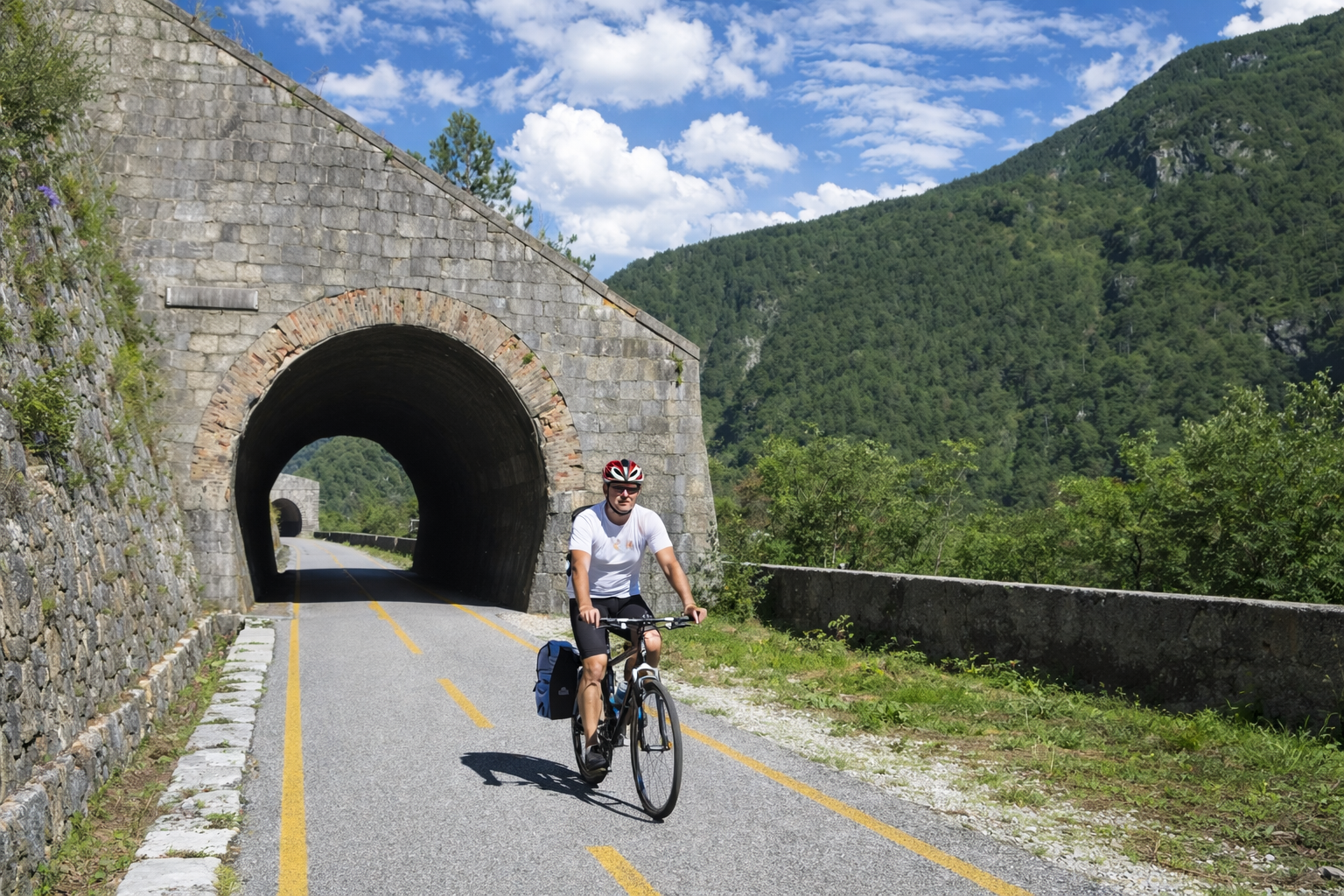 Cicloturista sulla ciclovia Alpe Adria mentre attraversa una galleria in montagna