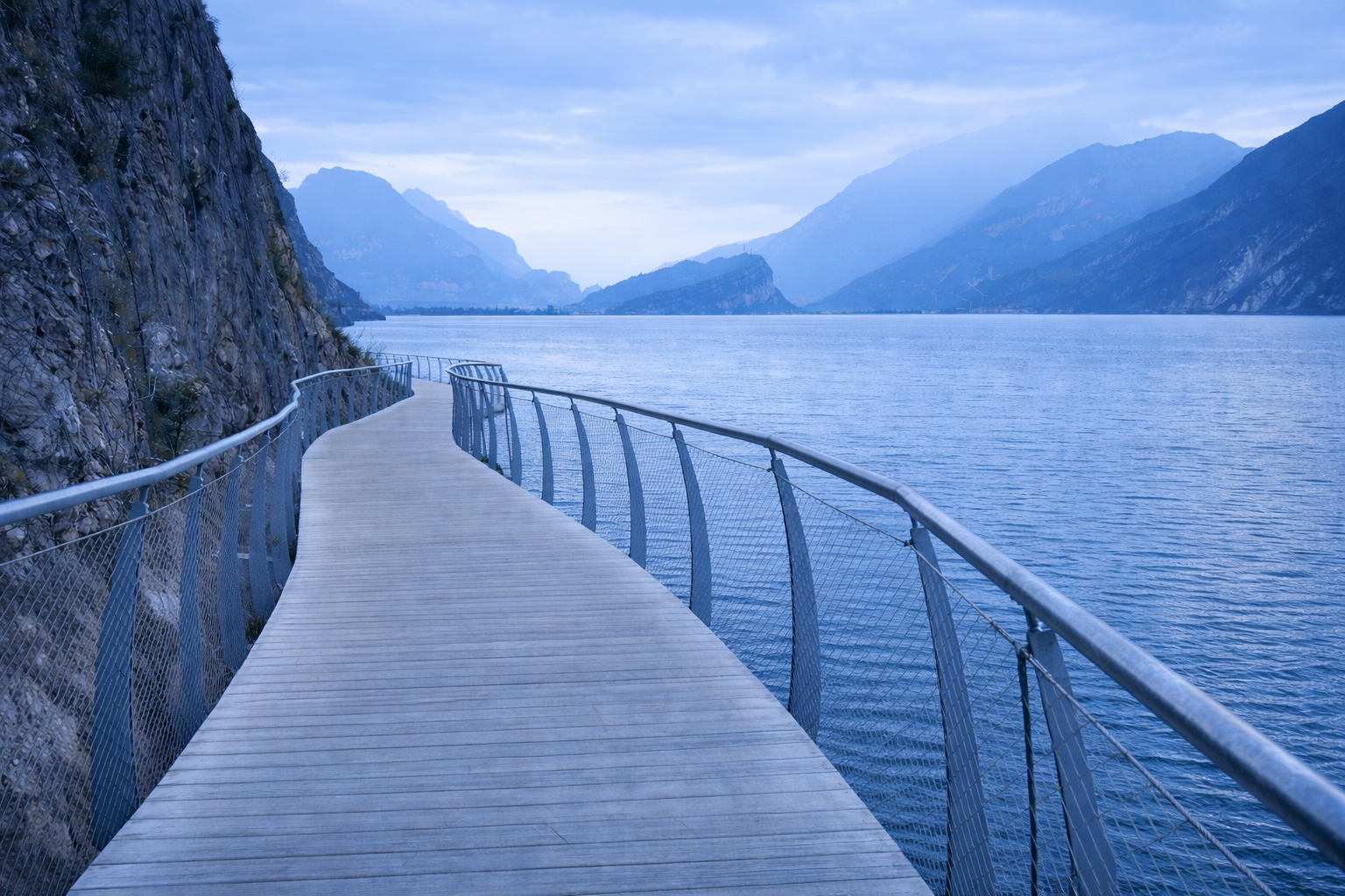 Pista ciclabile sospesa sul Lago di Garda con vista su montagne e acqua