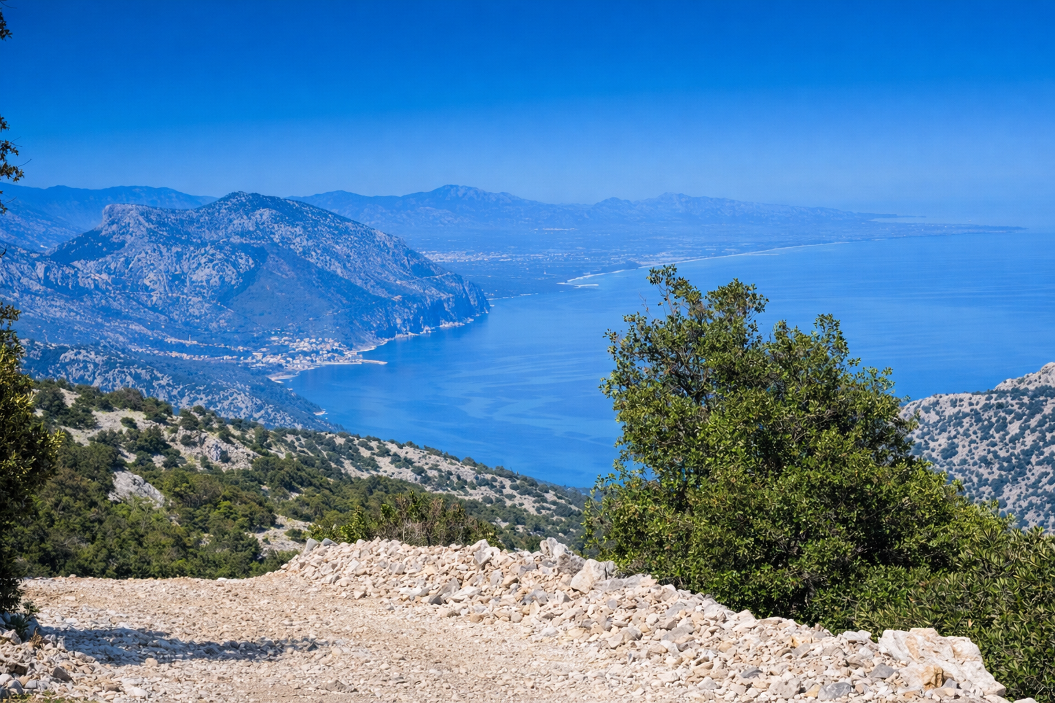 Vista panoramica della ciclovia della Sardegna lungo la costa con mare azzurro e montagne