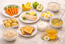 Tavola in stile flat lay con riso bianco, carote lesse, pesce al vapore con limone, uova sode, yogurt, patate, pane tostato, banane, mela cotta e tisana, alimenti utili per le feci molli