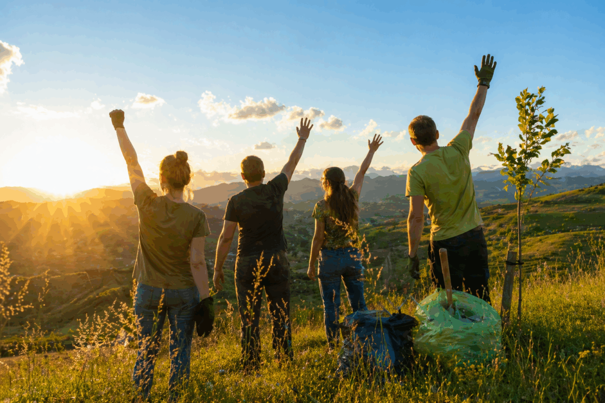 Persone nella natura al tramonto con le braccia alzate durante un’attività di tutela ambientale per la Giornata della Terra