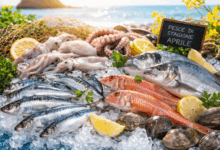 Selezione di pesce fresco di stagione ad aprile su ghiaccio con sardine, triglie, orata, calamari e limoni in un mercato sul mare