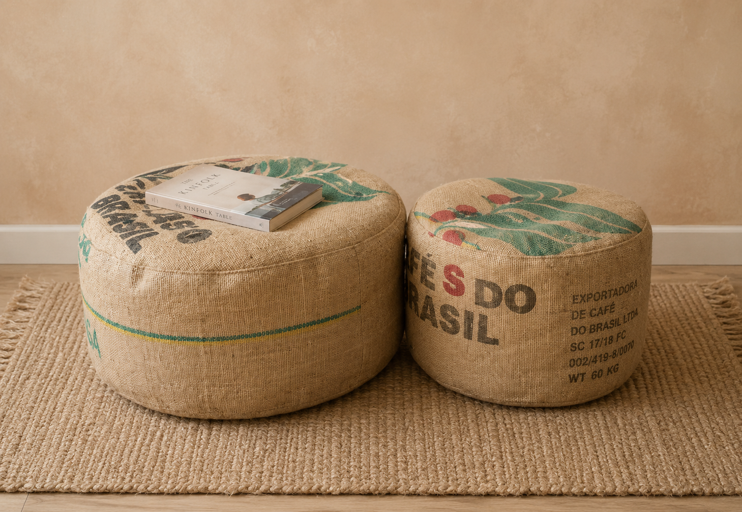 Due pouf rotondi fai-da-te realizzati con vecchi sacchi di juta da caffè, appoggiati su un tappeto naturale in una stanza con parete beige, con un libro sopra uno dei pouf