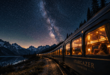 Treno panoramico illuminato sotto un cielo stellato con Via Lattea tra montagne e lago, immagine per articolo sui migliori stargazing trains