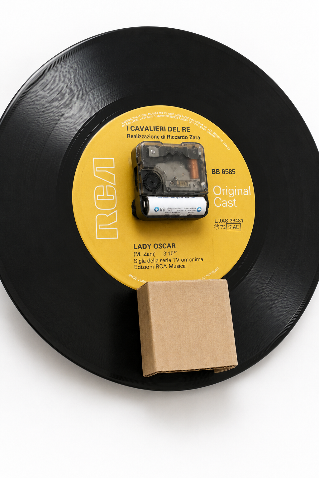 Retro di un vecchio disco in vinile 33 giri con movimento dell’orologio inserito nel foro centrale e supporto in cartone per fissare il meccanismo