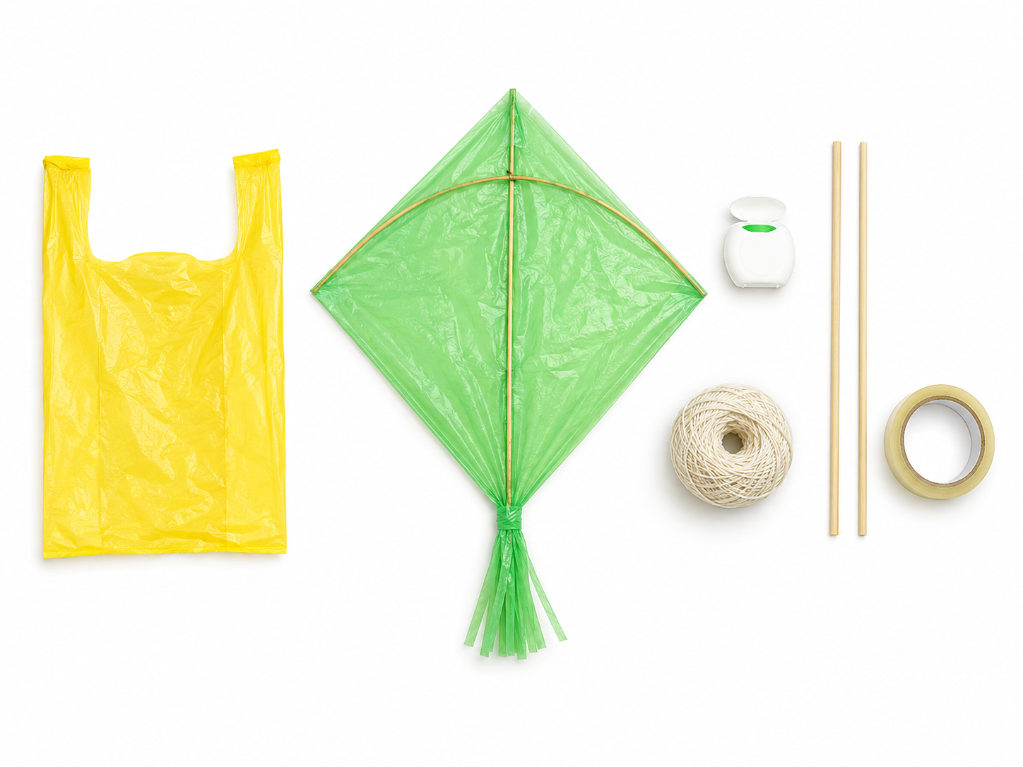 Occorrente per realizzare un aquilone fai da te con un sacchetto di plastica: sacchetto giallo, aquilone montato, filo interdentale, spago, stecche di legno e nastro adesivo su fondo bianco
