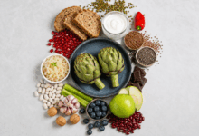 Composizione di cibi utili per nutrire il microbiota intestinale, con yogurt, crauti, pane integrale, carciofi, semi di lino, semi di chia, frutta, legumi e verdure