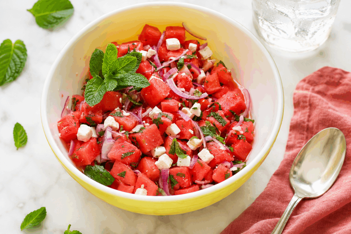 Insalata in ciotola bianca e gialla con insalata di anguria e feta con aroma di menta rinfrescante pr l'estate