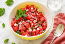 Insalata in ciotola bianca e gialla con insalata di anguria e feta con aroma di menta rinfrescante pr l'estate