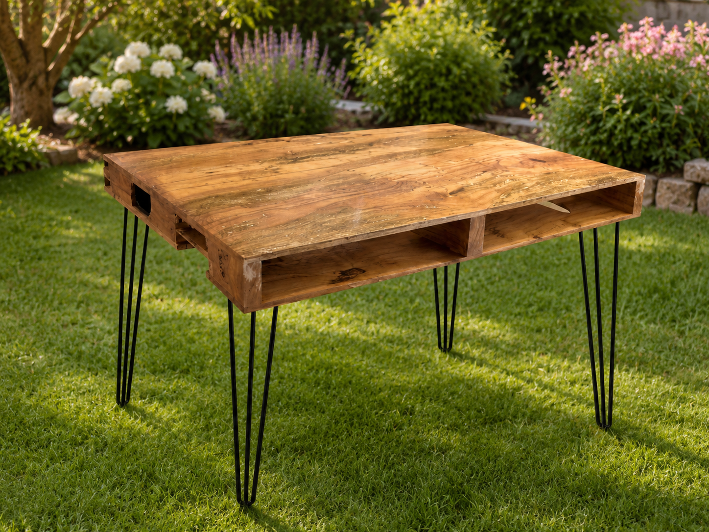 Tavolo in legno stile pallet con gambe in metallo nero, posizionato su un prato in giardino