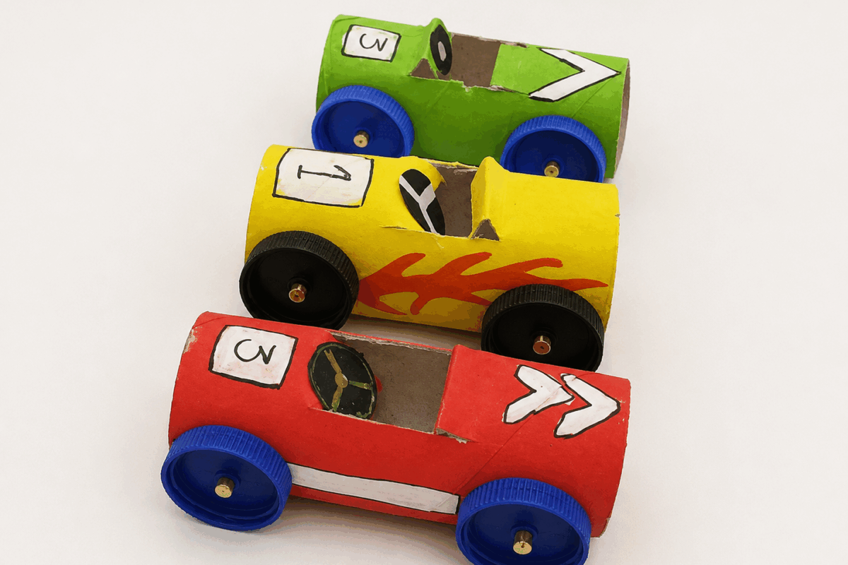 Tre automobiline fai-da-te realizzate con rotoli di carta igienica e tappi di plastica colorati usati come ruote.
