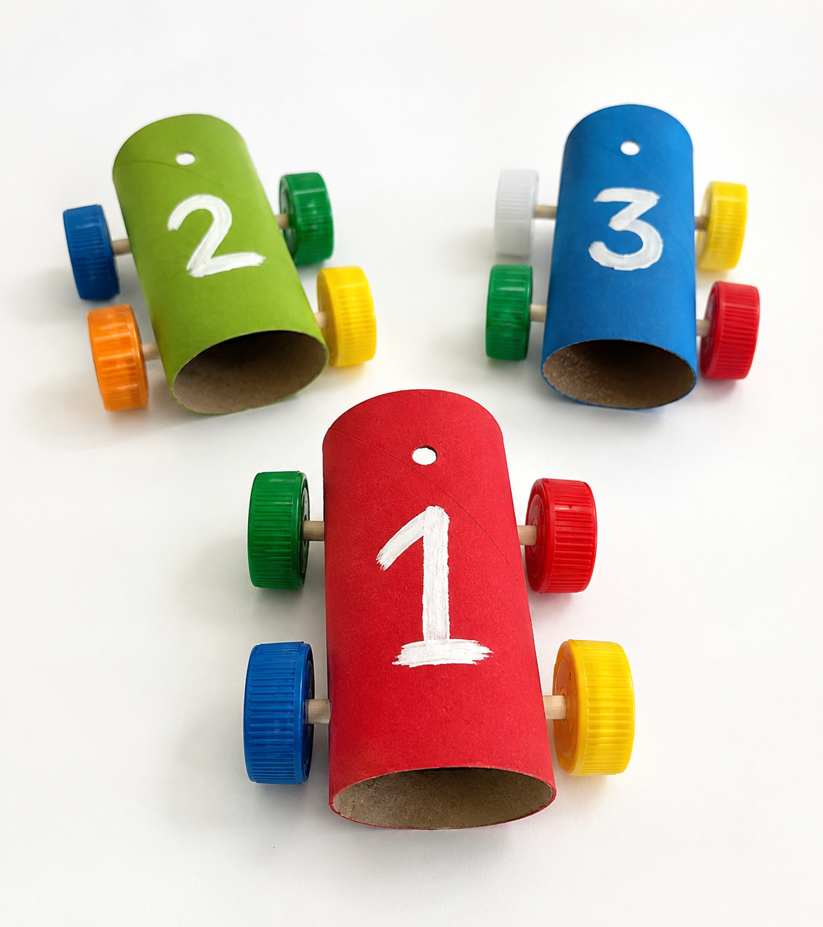 Macchinine fai-da-te realizzate con rotoli di carta igienica colorati, tappi di plastica come ruote e numeri dipinti a mano