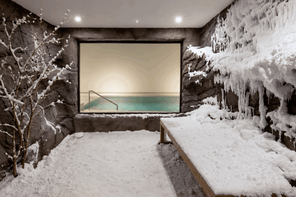 Snow room di lusso con pareti innevate, alberello coperto di neve e piscina sullo sfondo